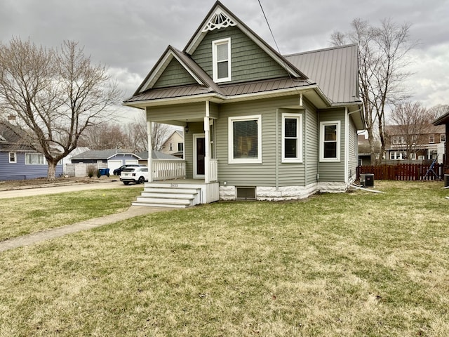 view of front of house featuring metal roof, a front lawn, and fence