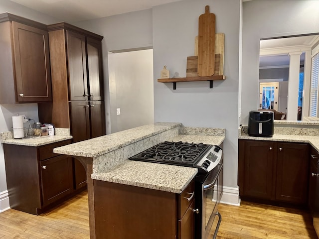 kitchen featuring light wood finished floors, stainless steel range with gas stovetop, a peninsula, and open shelves
