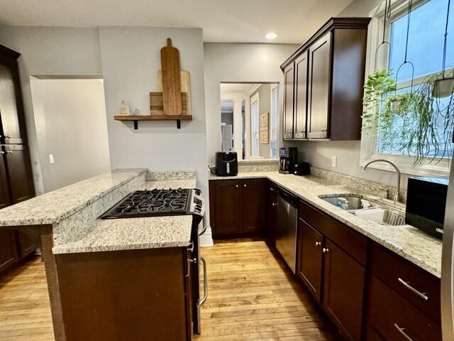 kitchen with dishwasher, light wood-type flooring, a peninsula, gas stove, and a sink