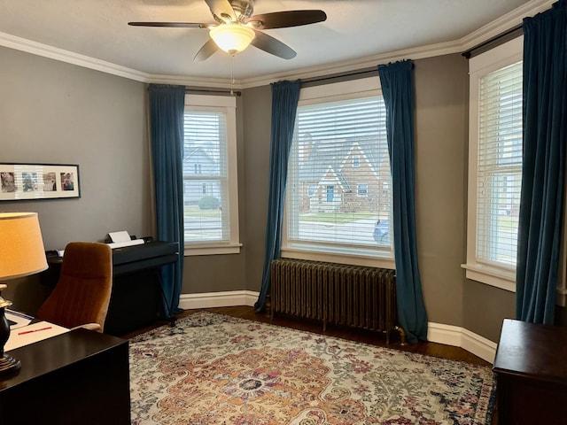 office space with radiator, baseboards, ornamental molding, wood finished floors, and a ceiling fan