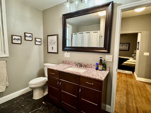 bathroom featuring toilet, vanity, and baseboards