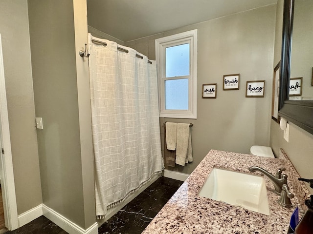 full bath with curtained shower, vanity, and baseboards