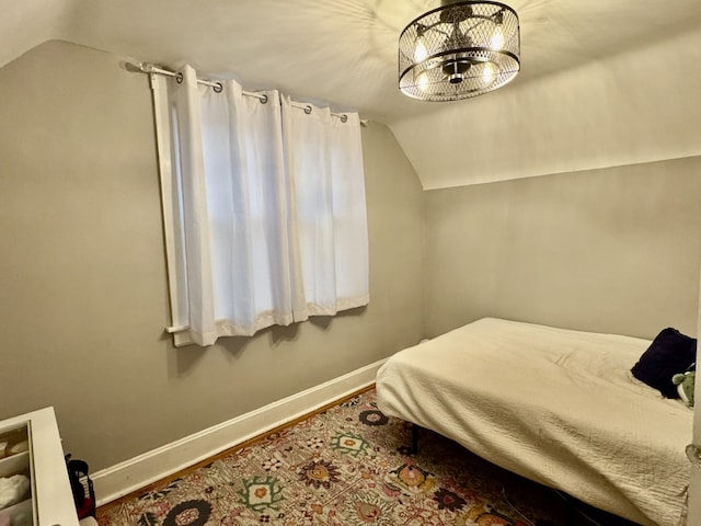 bedroom with vaulted ceiling, wood finished floors, and baseboards