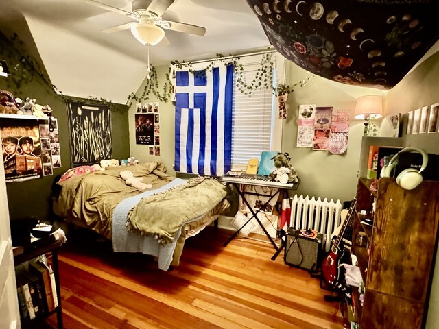 bedroom with a ceiling fan, vaulted ceiling, and wood finished floors