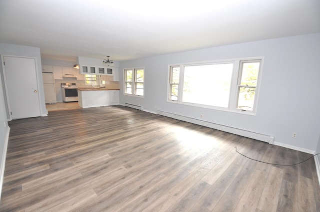 24109 64th Pl, Paddock Lake, WI 53168 - unfurnished living room featuring baseboard heating, a chandelier, dark wood finished floors, and baseboards