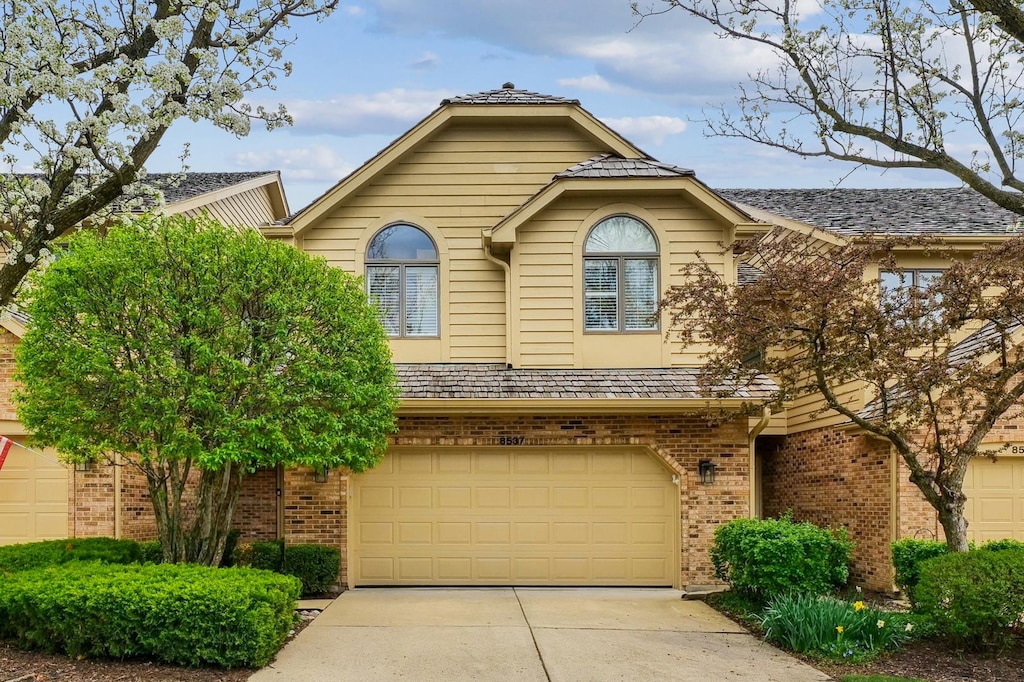 view of front of property featuring a garage, brick siding, and driveway