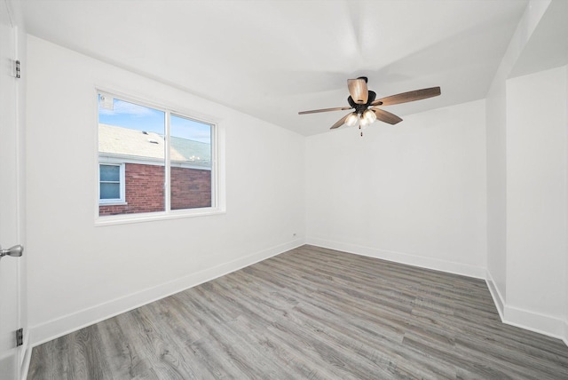 spare room with baseboards, wood finished floors, and ceiling fan