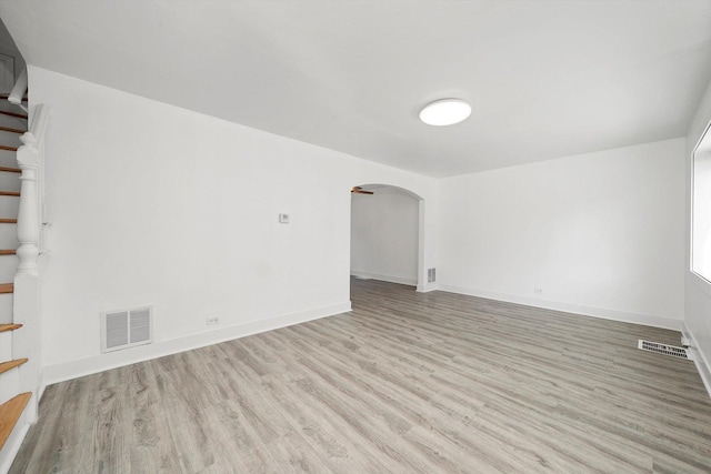 spare room with stairs, visible vents, wood finished floors, and arched walkways