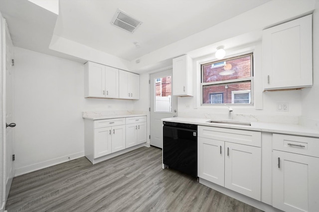 kitchen featuring white cabinetry, a sink, light wood finished floors, visible vents, and black dishwasher