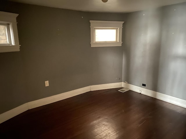 unfurnished room featuring visible vents, wood finished floors, and baseboards