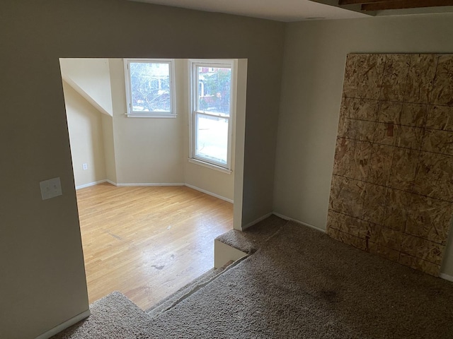spare room with baseboards and wood finished floors