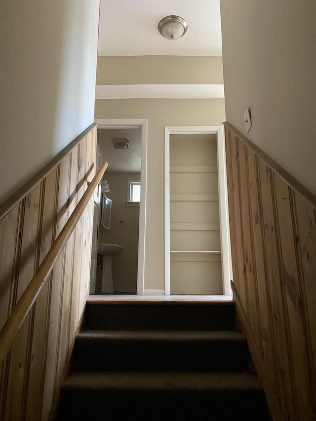 stairway with a wainscoted wall