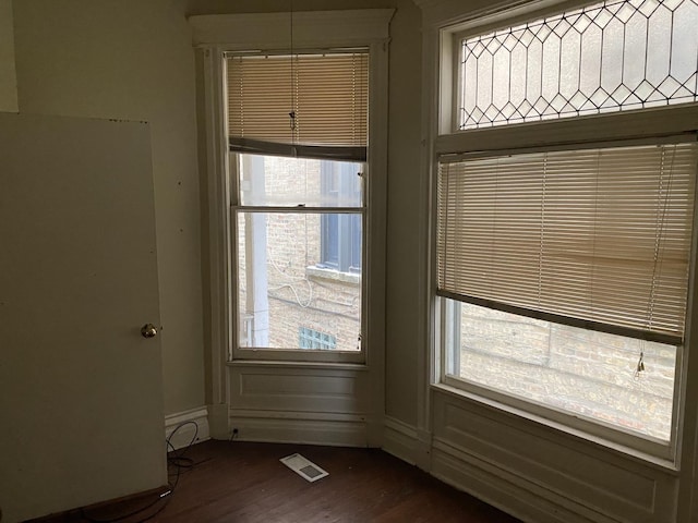 unfurnished dining area featuring visible vents, a healthy amount of sunlight, baseboards, and dark wood-style flooring