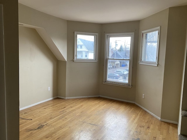 additional living space with baseboards and light wood-style floors