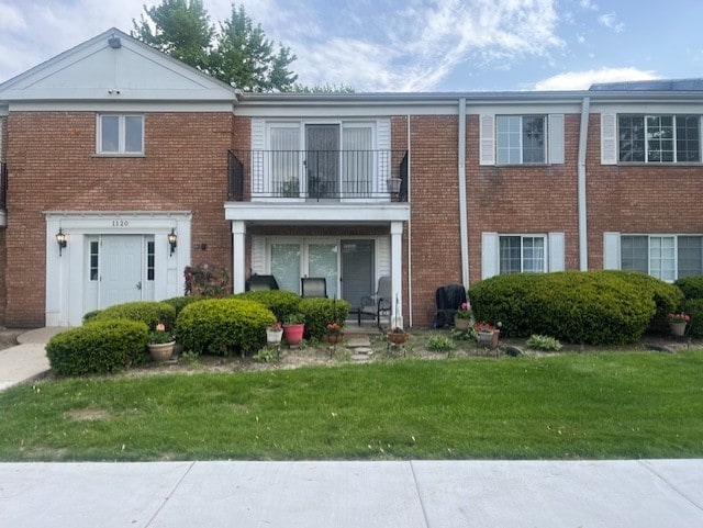 1120 N Farnsworth Ave Unit 2F, Aurora, IL 60505 - view of front facade featuring a balcony, a front lawn, and brick siding