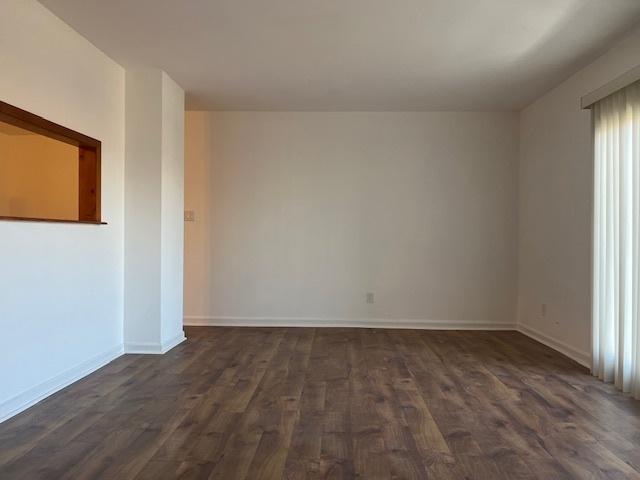 empty room with dark wood-type flooring and baseboards