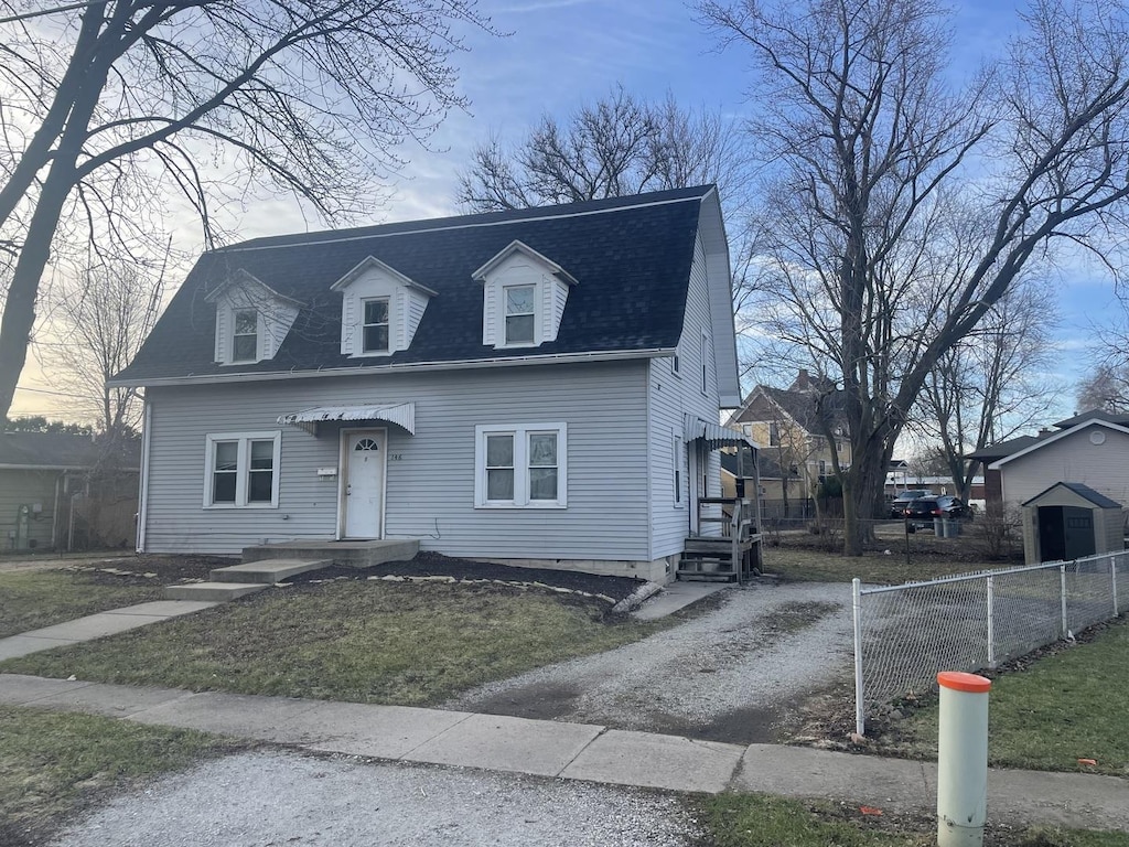view of front of house with driveway, a shingled roof, and fence