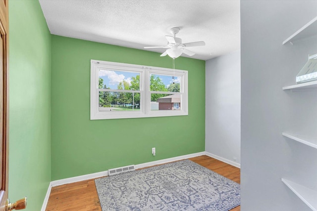 313 W Church St, Savoy, IL 61874 - empty room with a textured ceiling, a ceiling fan, baseboards, wood finished floors, and visible vents