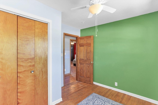 313 W Church St, Savoy, IL 61874 - unfurnished bedroom featuring a ceiling fan, baseboards, wood finished floors, and a closet