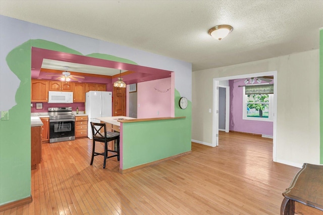 313 W Church St, Savoy, IL 61874 - kitchen with white appliances, light wood-style floors, light countertops, a textured ceiling, and brown cabinets