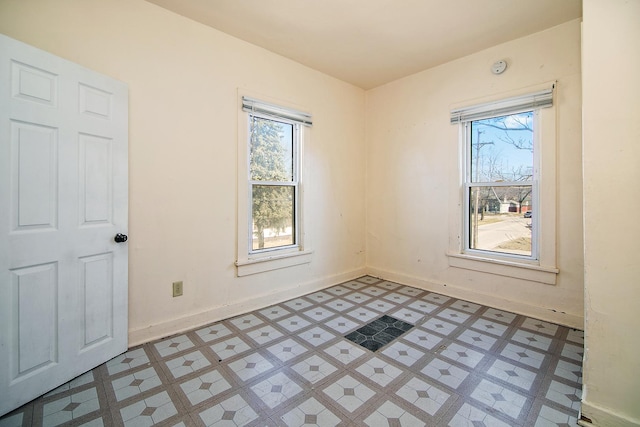 empty room with a wealth of natural light, baseboards, and light floors