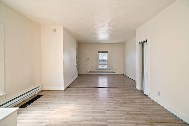 spare room featuring baseboards, a baseboard heating unit, light wood-style floors, and a baseboard radiator