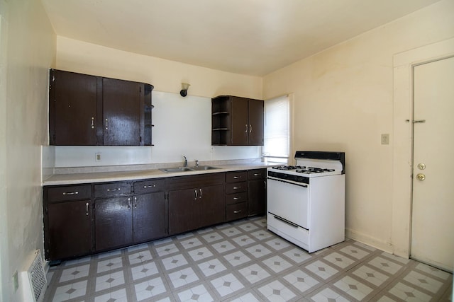 kitchen with light floors, visible vents, open shelves, white gas stove, and a sink