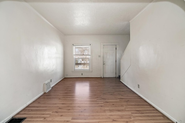 spare room with visible vents, light wood-style flooring, and crown molding