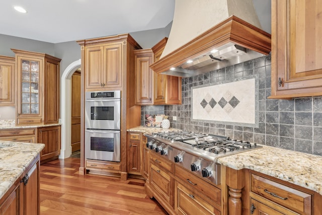 831 Alberosky Way, Batavia, IL 60510 - kitchen with premium range hood, appliances with stainless steel finishes, light wood finished floors, light stone countertops, and decorative backsplash