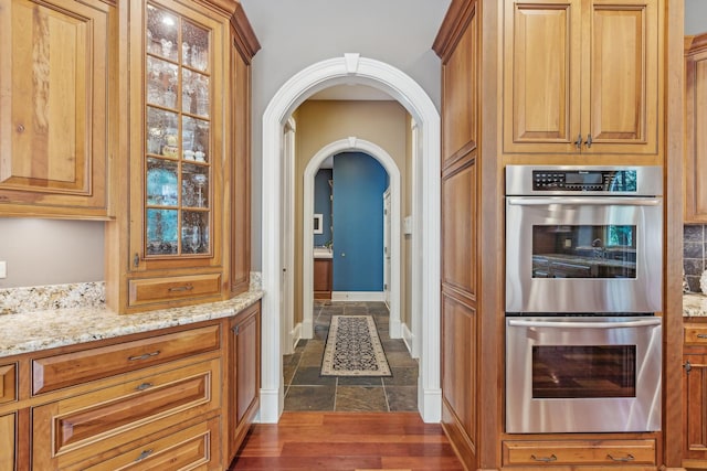 831 Alberosky Way, Batavia, IL 60510 - kitchen with stainless steel double oven, light stone counters, stone tile floors, arched walkways, and brown cabinets