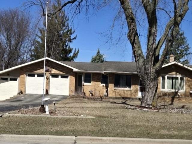 ranch-style home with a chimney, an attached garage, and driveway