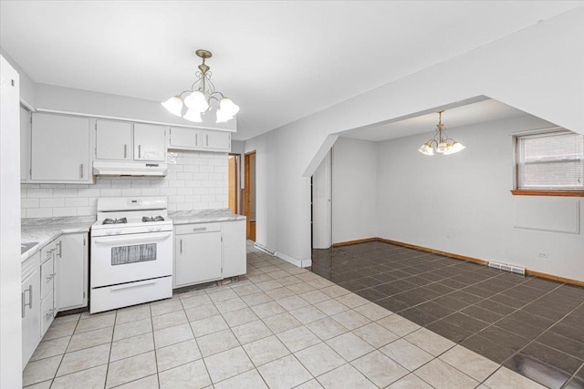 5817 W 16th St, Cicero, IL 60804 - kitchen featuring light countertops, gas range gas stove, under cabinet range hood, a chandelier, and backsplash