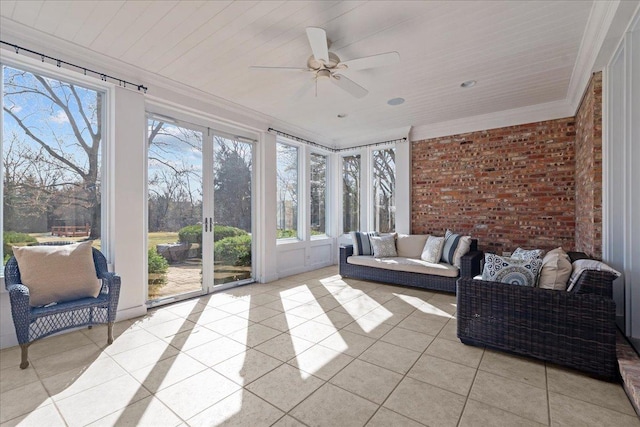 sunroom / solarium featuring a ceiling fan, tile patterned floors, crown molding, and brick wall