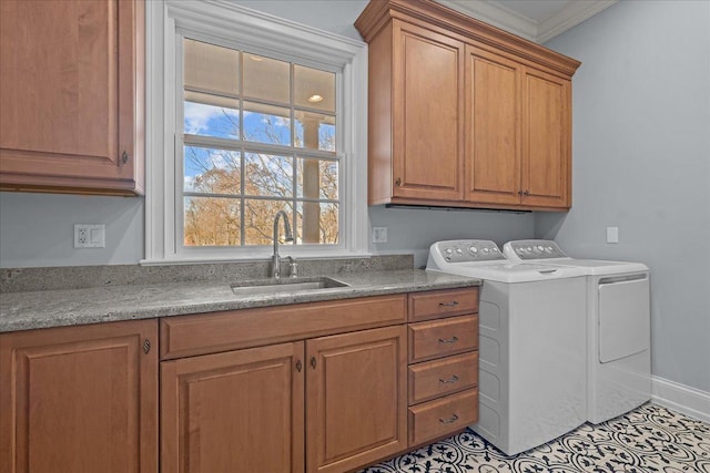 clothes washing area with crown molding, a sink, baseboards, independent washer and dryer, and cabinet space