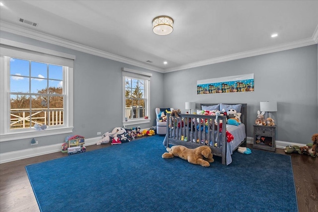 bedroom with visible vents, crown molding, baseboards, and wood finished floors