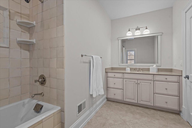 bathroom with vanity, tile patterned flooring, baseboards, visible vents, and tiled shower / bath