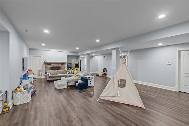playroom with visible vents, baseboards, wood finished floors, recessed lighting, and a stone fireplace