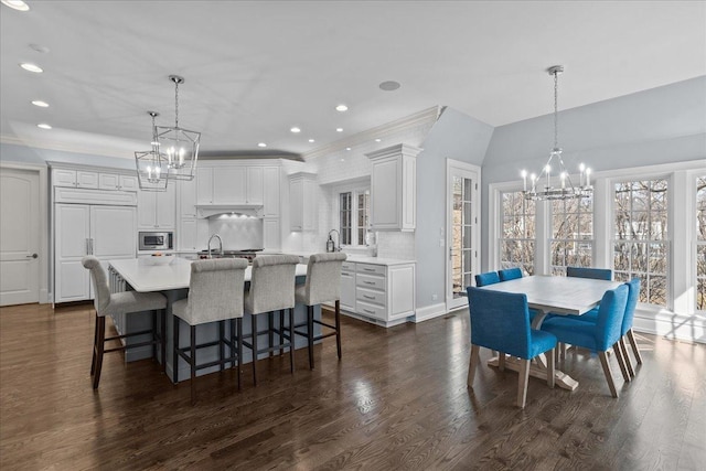 dining area with dark wood-style flooring, vaulted ceiling, recessed lighting, and a notable chandelier