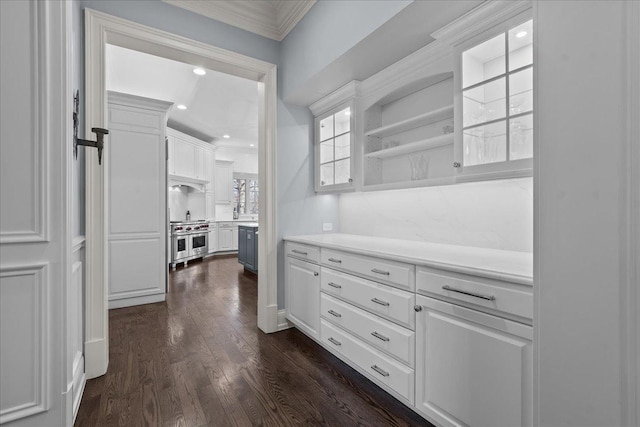 interior space with light countertops, double oven range, white cabinetry, ornamental molding, and dark wood-style flooring