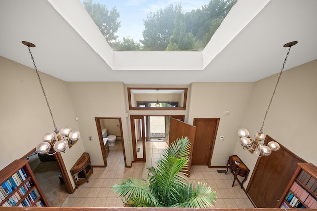interior space with light tile patterned floors, a notable chandelier, a skylight, and baseboards