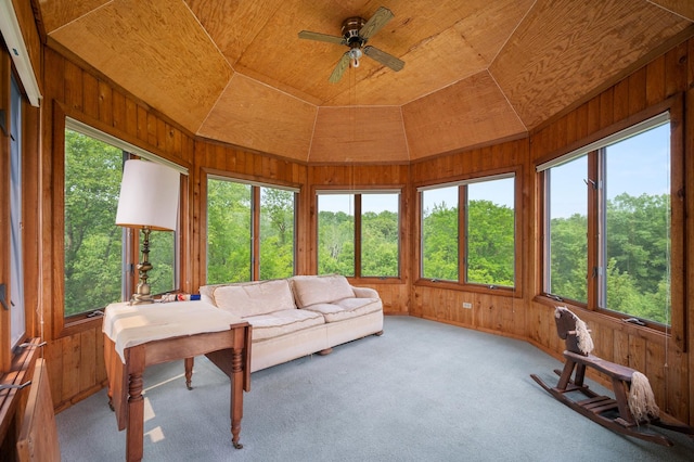 sunroom featuring vaulted ceiling, wooden walls, and carpet floors