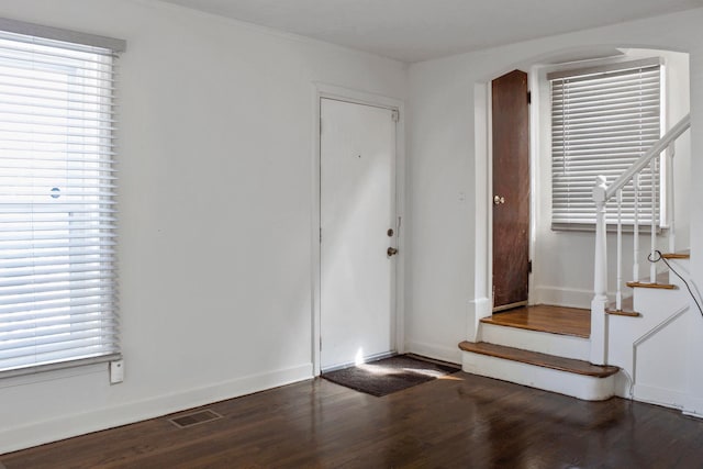entryway with stairway, baseboards, arched walkways, visible vents, and wood finished floors