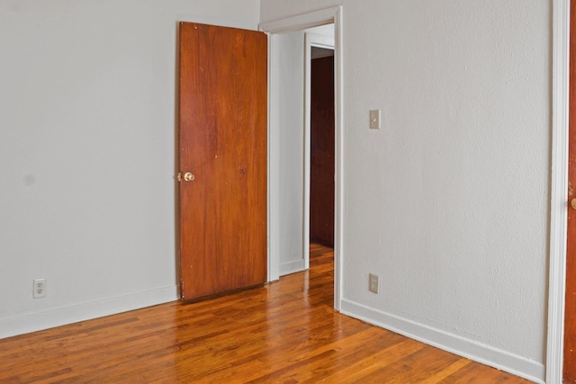spare room with baseboards and wood finished floors