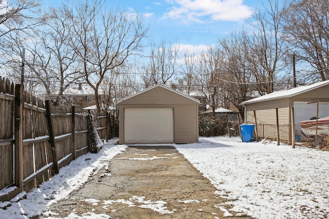 snow covered garage featuring a garage and fence