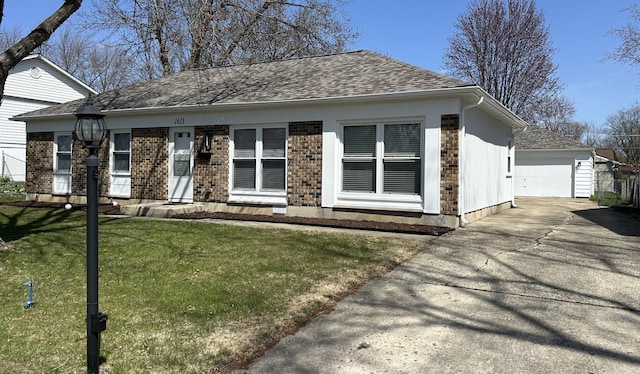 view of front of property with a shingled roof, a garage, an outdoor structure, brick siding, and a front lawn