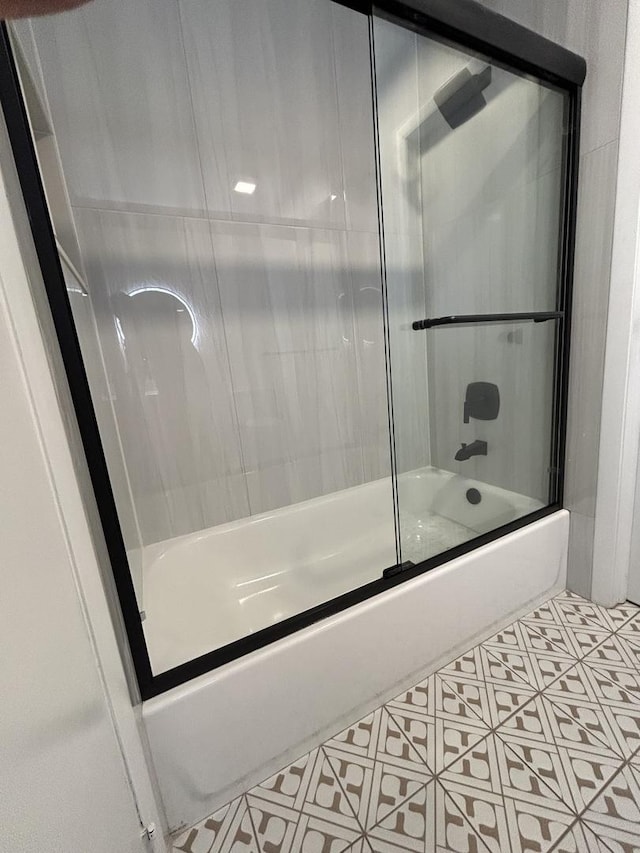 bathroom with tile patterned flooring and bath / shower combo with glass door