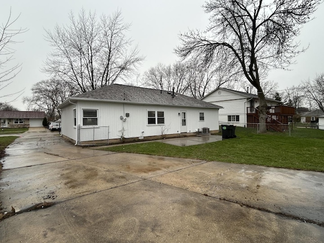 rear view of property featuring central AC, a lawn, a patio, fence, and concrete driveway