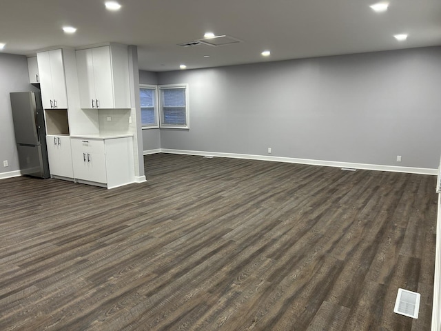 interior space featuring baseboards, open floor plan, light countertops, freestanding refrigerator, and dark wood-type flooring