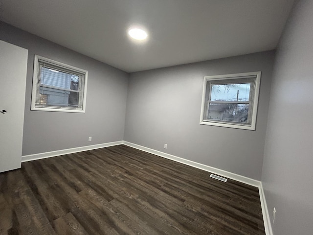 spare room featuring dark wood-style flooring, baseboards, and visible vents