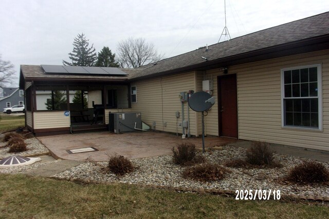 507 N Fifth St, Ashkum, IL 60911 - rear view of house with roof mounted solar panels, a shingled roof, central AC, and a patio